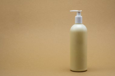 Tarafsız bir bej arka planda, pompa kutusuyla sade bir plastik losyon şişesi. Cilt bakımı, kozmetik veya kişisel bakım ürünleri için ideal.