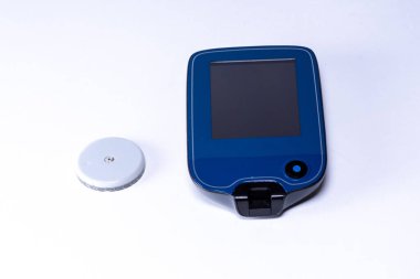 İnsülin pompası ve sürekli glikoz izleme sensörü beyaz yüzeyde yatıyor, hastaların şeker hastalığını kontrol altına almalarına ve kan şekerini etkili bir şekilde kontrol etmelerine yardımcı oluyor.