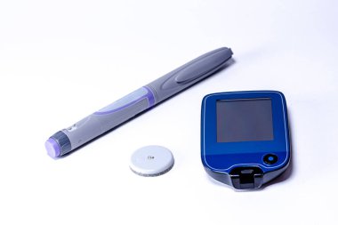 İnsülin kalem, cgm ve sensör beyaz bir yüzeyde yatıyor, diyabet yönetimine kapsamlı bir yaklaşım sunuyor ve kan şekeri kontrolünün önemini vurguluyor