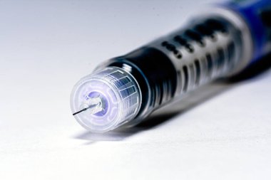 Beyaz bir yüzeye uzanan insülin kalem, diyabet tedavisi için hormon enjekte etmek, hastaların kan şekeri seviyelerini kontrol etmelerine yardımcı olmak ve genel sağlık durumunu korumak.