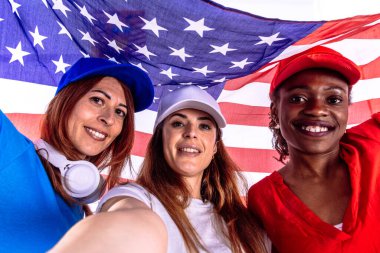 4 Temmuz kutlamaları sırasında elinde bir Amerikan bayrağı tutarak selfie çeken üç mutlu etnik kadın. Vatanseverlik kavramı, bağımsızlık günü