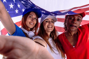 Büyük bir Amerikan bayrağı taşıyan üç mutlu kadın bağımsızlık gününü kutluyor vatanseverliği ve ulusal gururu ifade ediyorlar. Vatanseverlik kavramı, bağımsızlık günü