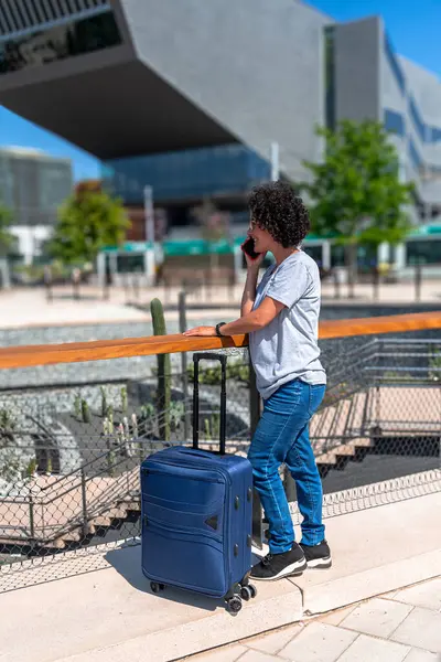 Dijital göçebe, modern bir şehirde otobüs durağında beklerken, uzaktan çalışma ve seyahatin özgürlüğünü ve esnekliğini simgeleyen bir telefon görüşmesi yapıyor.