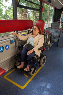 Erişilebilir bir otobüsle seyahat eden kendine güvenen bir iş kadını, kapsamlı bir altyapı ihtiyacını vurguluyor. Katılım kavramı, uyarlanmış toplu taşıma