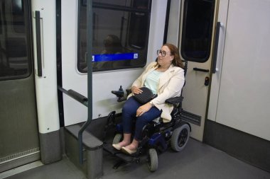 Modern bir tekerlekli sandalyede oturan iş kadını engelliler için giriş rampası ile donatılmış bir metro treni kullanıyor, dahil olma ve hareket kabiliyetini arttırıyor. Katılım kavramı, uyarlanmış toplu taşıma