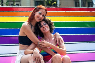 İki kadın gökkuşağı renkli basamakları kucaklıyor, bir gurur etkinliği sırasında lgbtq artı topluluğa olan sevgilerini ve desteklerini simgeliyorlar, çeşitliliği, dahil olmayı ve eşit haklara sahip olmayı destekliyorlar.