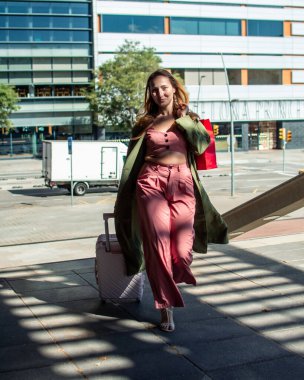 Modern şehir ortamında alışveriş çantaları ve tramvayla gezen modacı başarılı bir alışveriş çılgınlığından sonra güneşli bir sonbahar gününün tadını çıkarıyor.