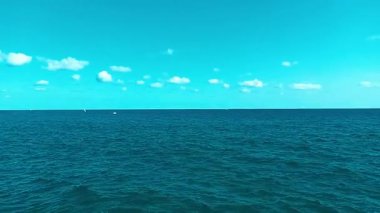 Güzel turkuaz sular, sakin mavi bir gökyüzü altında hafif dalgalanır. Küçük beyaz bulutlarla benekli, Torredembarra, İspanya 'daki Akdeniz' in sakin güzelliğini gözler önüne serer.