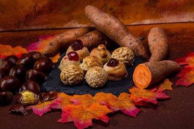 Tabakta çeşitli paneller, badem bazlı küçük tatlılar, kavrulmuş kestaneler ve tatlı patateslerin yanında, Castanyada 'nın katalan kutlamaları için şenlikli bir sahne var.