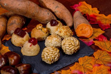 Geleneksel katalan tatlıları, panelletler, kestaneler ve tatlı patatesler sonbahar yapraklı bir masada güzelce düzenlenir ve Castanyada kutlamaları için şenlikli bir sahne yaratır.