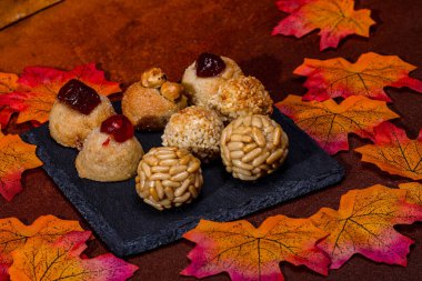 Panellet adı verilen küçük badem ezmesi kekleri, çam fıstığı, şekerli meyve ve fındıklı, sonbahar yapraklı bir tahta tabakta dinleniyor, katalonya 'nın Castanyada' sını kutluyorlar.