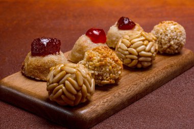 Çam fıstığı, şekerli meyve ya da hindistan cevizi talaşı ile kaplı küçük badem ezmesi kekleri, yanında kastanyada kutlaması için katalonya, İspanya 'da ahşap bir tahtaya dizilmiş kızarmış tatlı patatesler.