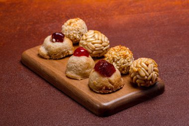 Küçük, yuvarlak paneletler, bazıları çam fıstığıyla kaplanmış ve diğerleri şekerli meyvelerle kaplı, tahta bir tahtada dinleniyor, katalonya 'da castanyada' yı kutluyorlar.