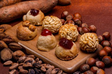 Çam fıstığı, fındık, badem ve tatlı patateslerle çevrili ahşap bir tahtanın üzerinde oturan castanyada için tipik katalan tatlıları, küçük paneletler, şenlikli bir sonbahar sahnesi yaratıyor.