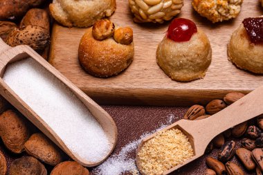 Tahta kepçeler badem ve şekeri sunar, kastanyada için geleneksel katalan tatlısı, çam fıstığı, şekerli meyve ve fındıklı, neşeli bir sahne yaratır.