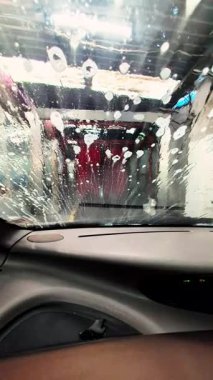 Otomatik araba yıkama sırasında ön camı kaplayan şeffaf sabun köpükleri, köpüklü katmanlardan yansıyan ışıkla dönen, yanardöner görsel efektler üretiyor.