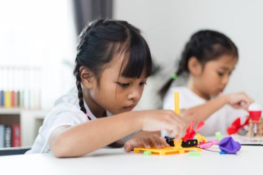 İki kardeş Asyalı kız evde yel değirmeni yığını oynuyorlar.