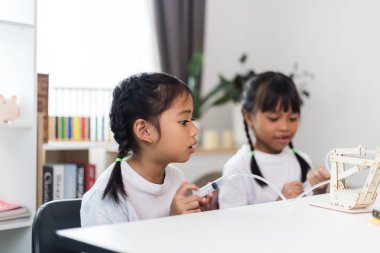 İki Asyalı kız hidrolik güçle çalışan mekanik kavrama çalışmaları üzerinde çalışıyor.