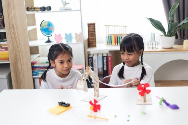 İki Asyalı kız hidrolik güçle çalışan mekanik kavrama çalışmaları üzerinde çalışıyor.