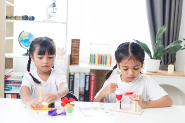 İki kardeş Asyalı kız evde yel değirmeni yığını oynuyorlar.