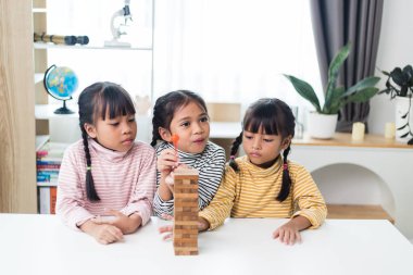 Üç kardeş Asyalı kız evde ahşap destelerle oynuyorlar.