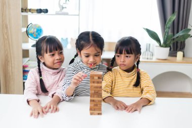 Üç kardeş Asyalı kız evde ahşap destelerle oynuyorlar.
