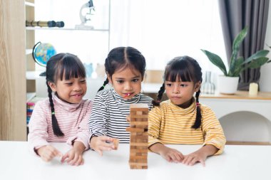 Üç kardeş Asyalı kız evde ahşap destelerle oynuyorlar.