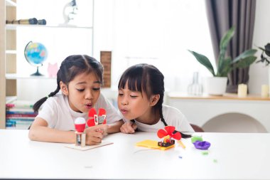 İki kardeş Asyalı kız evde yel değirmeni yığını oynuyorlar.