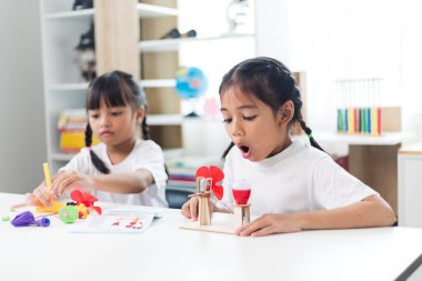 İki kardeş Asyalı kız evde yel değirmeni yığını oynuyorlar.