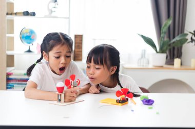 İki kardeş Asyalı kız evde yel değirmeni yığını oynuyorlar.