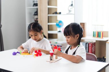 İki kardeş Asyalı kız evde yel değirmeni yığını oynuyorlar.