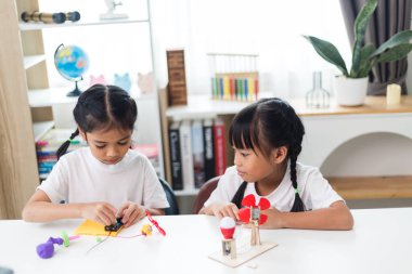 İki kardeş Asyalı kız evde yel değirmeni yığını oynuyorlar.