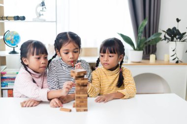 Üç kardeş Asyalı kız evde ahşap destelerle oynuyorlar.