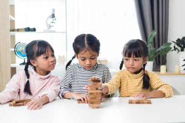 Üç kardeş Asyalı kız evde ahşap destelerle oynuyorlar.