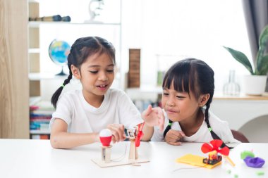 İki kardeş Asyalı kız evde yel değirmeni yığını oynuyorlar.