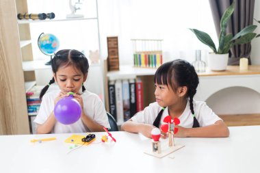 Evde balon şişirmece oynayan iki Asyalı kız.