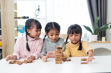 Üç kardeş Asyalı kız evde ahşap destelerle oynuyorlar.