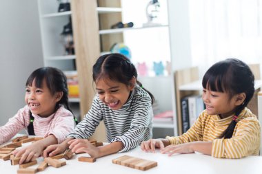 Üç kardeş Asyalı kız evde ahşap destelerle oynuyorlar.