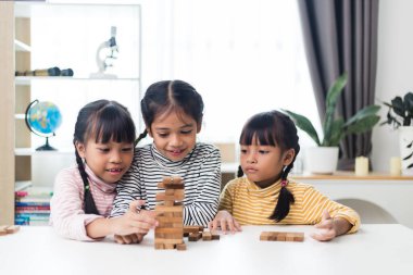 Üç kardeş Asyalı kız evde ahşap destelerle oynuyorlar.