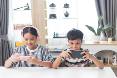 Asyalı çocuklar evde eğlenmek için arkadaşlarıyla çevrimiçi video oyunları oynuyorlar..