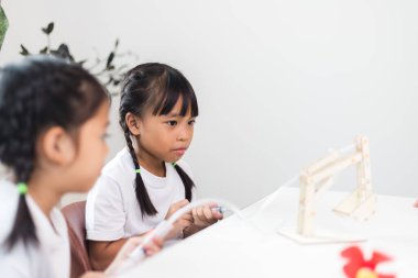 İki Asyalı kız hidrolik güçle çalışan mekanik kavrama çalışmaları üzerinde çalışıyor.