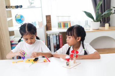 İki kardeş Asyalı kız evde yel değirmeni yığını oynuyorlar.