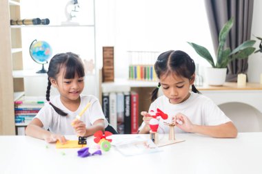 İki kardeş Asyalı kız evde yel değirmeni yığını oynuyorlar.