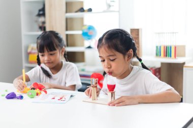 İki kardeş Asyalı kız evde yel değirmeni yığını oynuyorlar.