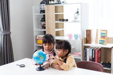 İki kardeş Asyalı evde coğrafya okuyor..