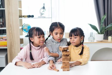 Üç kardeş Asyalı kız evde ahşap destelerle oynuyorlar.