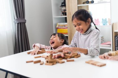 Üç kardeş Asyalı kız evde ahşap destelerle oynuyorlar.