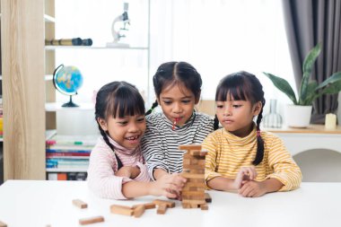 Üç kardeş Asyalı kız evde ahşap destelerle oynuyorlar.