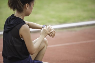 Genç bir kadın antrenman için hazırlanıyor, spor takımlarını ayarlıyor ve mesafeyi takip etmek için ukalalığını ayarlıyor, spor hedeflerini fethetmeye hazırlanırken gözleri kararlılıkla parıldıyor..