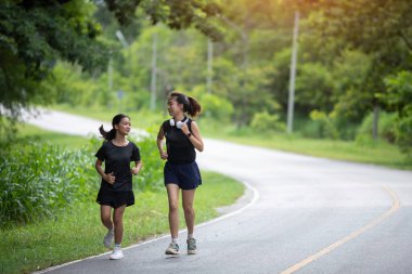 Genç bir kadın ve küçük kız kardeşi sabah egzersizleri için yan yana koşuyorlar, gülüşleri ve senkronize adımları kardeşçe bağlılık ve kararlılığın canlı bir sahnesini yaratıyor..